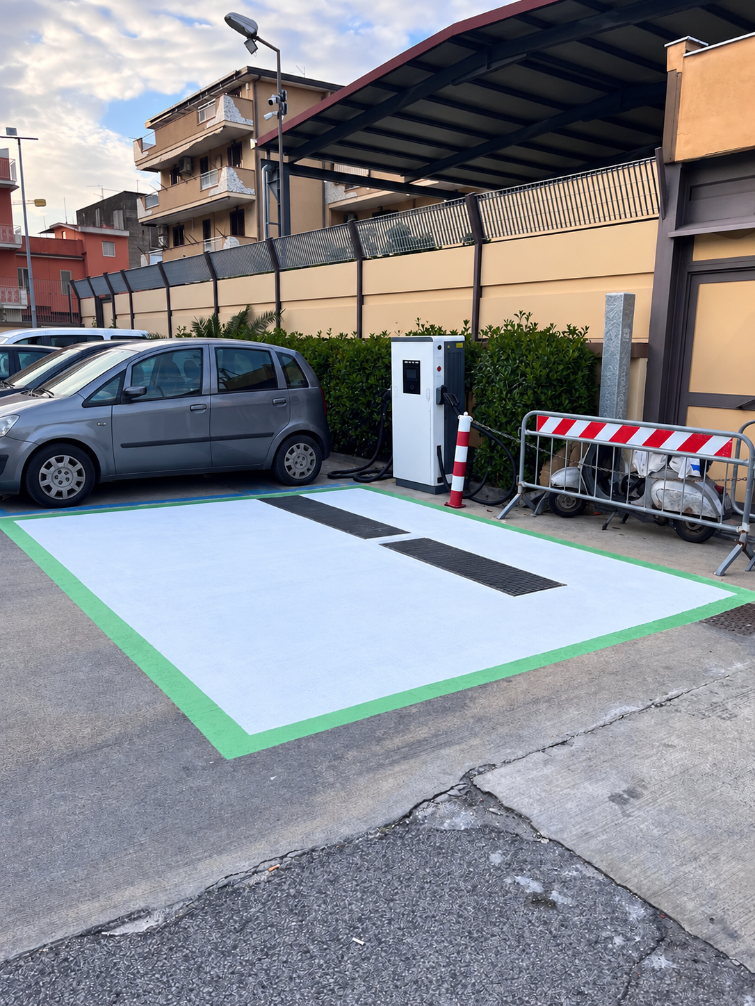 Supplied Italy installation-context photo showing a DC cabinet beside a parked vehicle