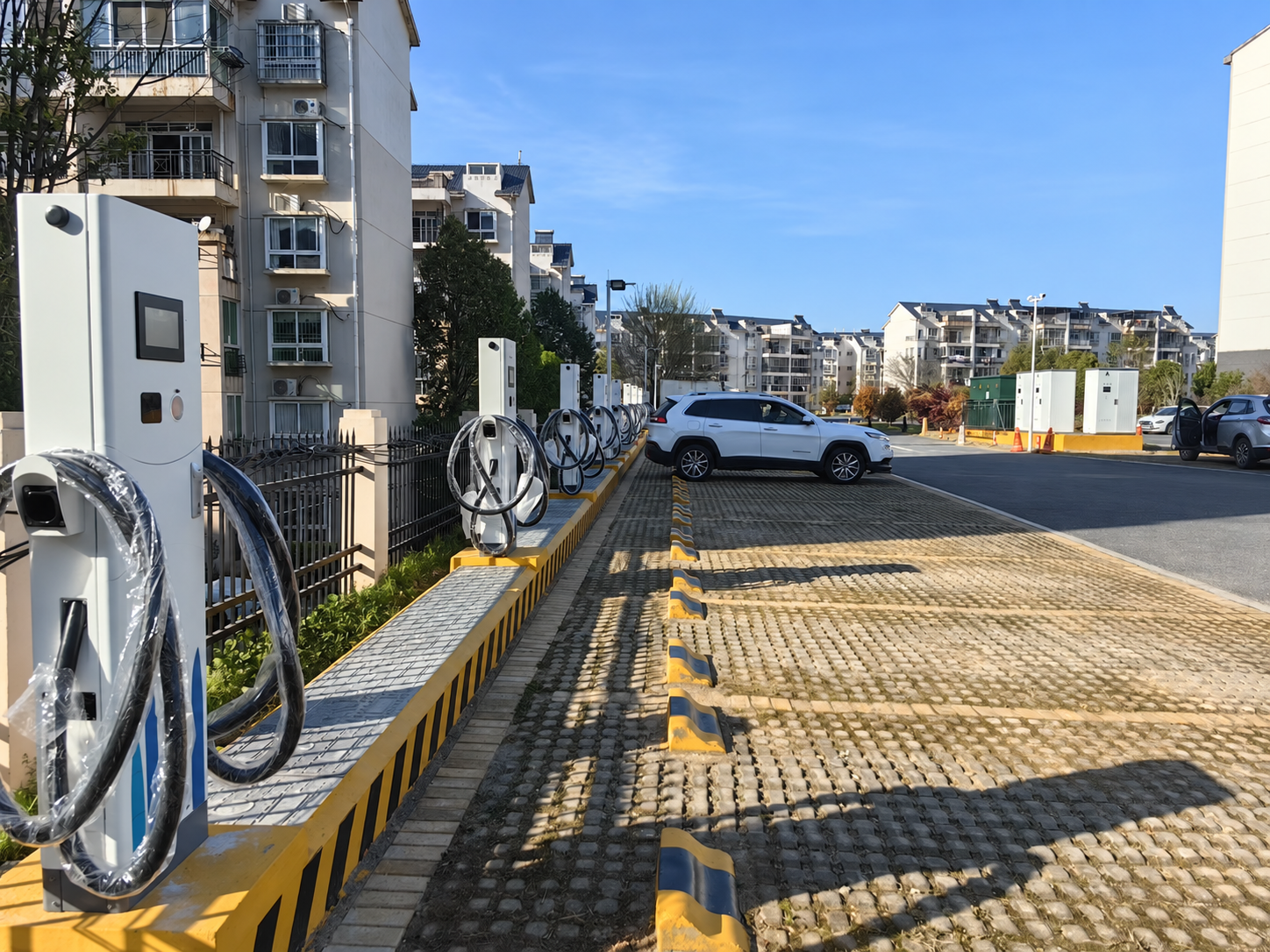 Supplied DC charging-site photograph showing charging bays, dispensers and a parked vehicle